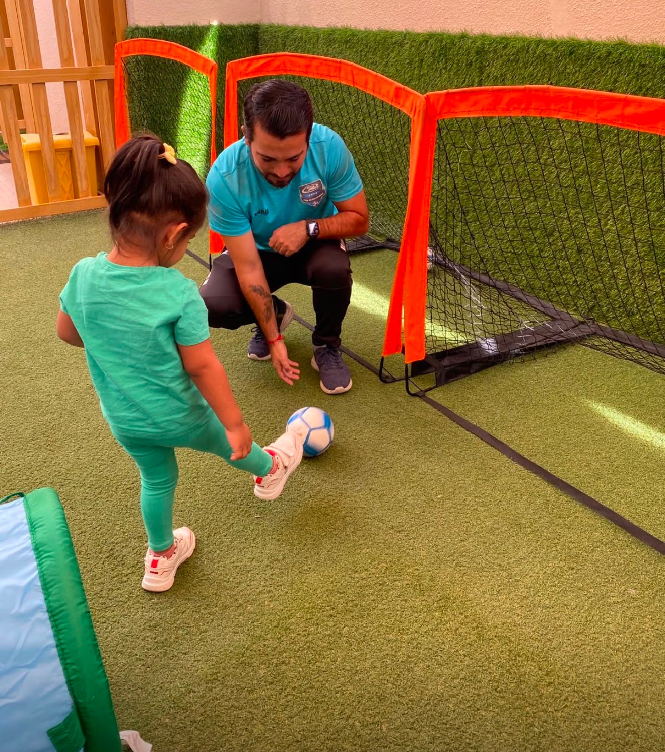 Coach guiding a child through a football drill