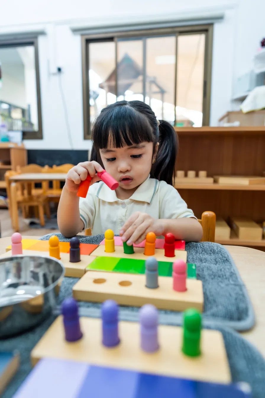 Girl practising colour matching with wooden peg boards