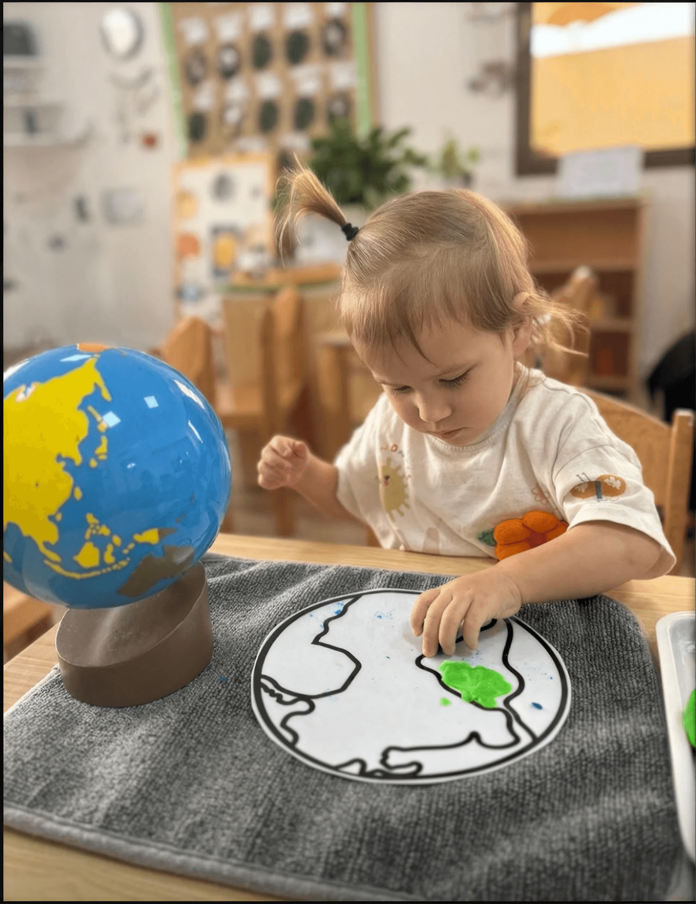 Toddler painting a globe craft activity at Ladybird Nursery